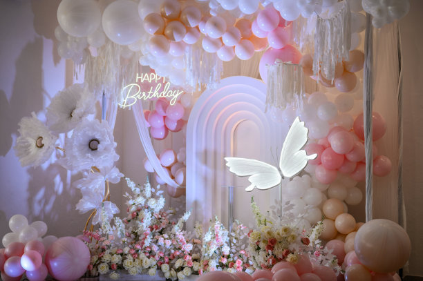 装饰纸蝴蝶。粉红色的拱门装饰，白色的气球，生日快乐的文字，装饰的鲜花。儿童照相区。背景照片墙上的小女孩生日派对。特写镜头。图片下载