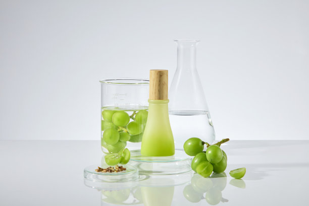 在白色的实验室台面中央展示着实验室，新鲜的绿葡萄和葡萄籽，围绕着一个没有标签的木盖瓶子。照片的正面视图与空白的空间来设计图片下载