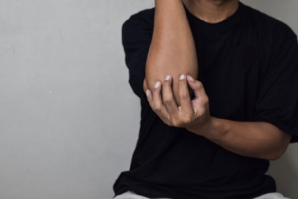 男子在运动受伤后用手按摩肘部，有点模糊图片下载