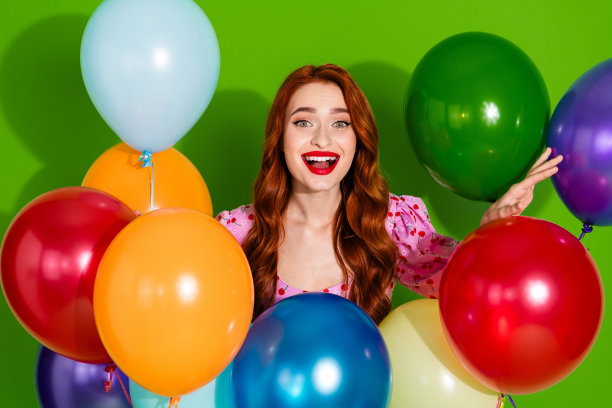 照片的兴奋积极的妇女穿着印花上衣拿着气球束空空间孤立的绿色背景图片下载