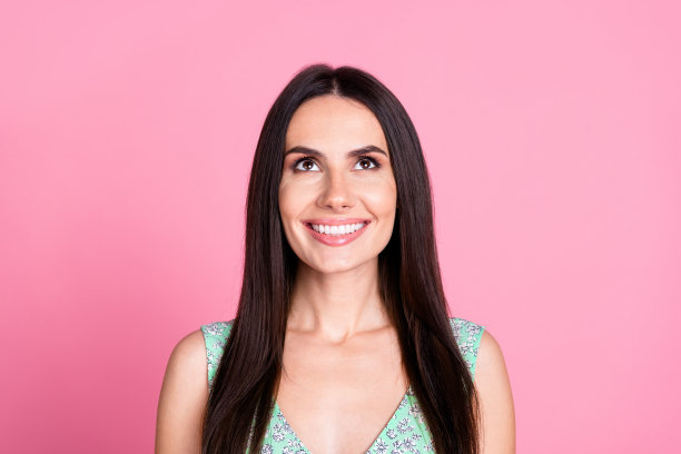 照片中，开朗可爱的魅力女人穿着时髦的衣服，仰望空旷的空间，孤立在粉红色的背景上图片下载