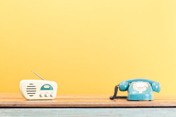 复古的电话和收音机在旧橡木木桌子前黄色背景。复古滤镜照片图片下载
