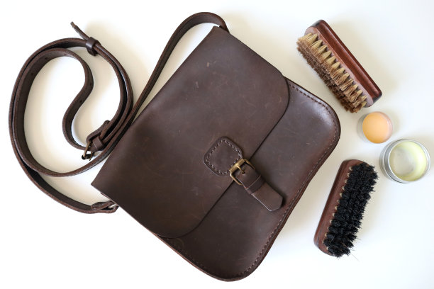 照片皮革手袋，刷子和清洁蜡。白色背景。图片下载