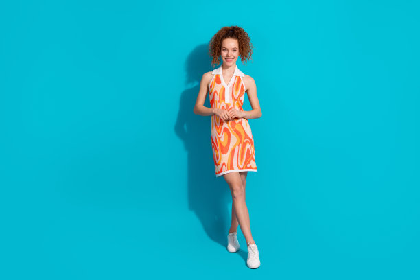 可爱的年轻女士的全身照片害羞的姿势模特穿着时尚的橙色服装孤立的青色背景图片下载