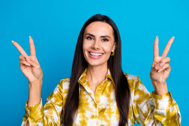 照片中开朗优雅的好女人穿着时尚的衣服，在蓝色背景上展示了v字图片下载