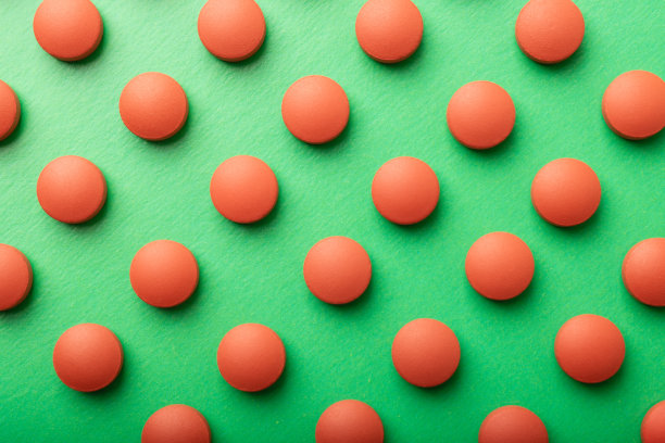 橙色圆形药丸在绿色背景俯视图。药物模式药丸特写。与药片紧密相连的平铺构图。医药行业背景纹理。医疗保健。高质量照片图片下载