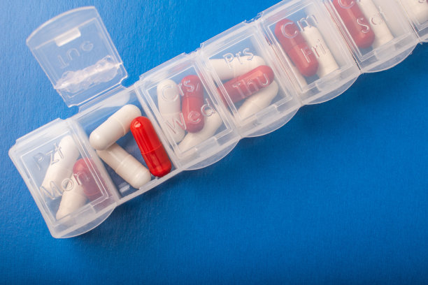 药盒与药丸和补品在蓝色背景，俯视图。胶囊在日常组织者。每周药片整理和药片。透明塑料药丸容器和药物。高质量照片图片下载