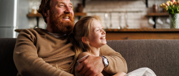 挂在横幅上的照片是满脸胡须的父亲在家里的沙发上拥抱青春期前的女儿图片下载