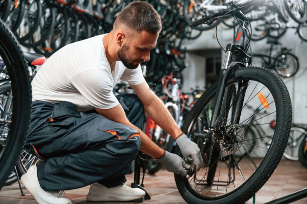 用手打气筒给轮胎充气。自行车店修理工，在店里工作图片下载