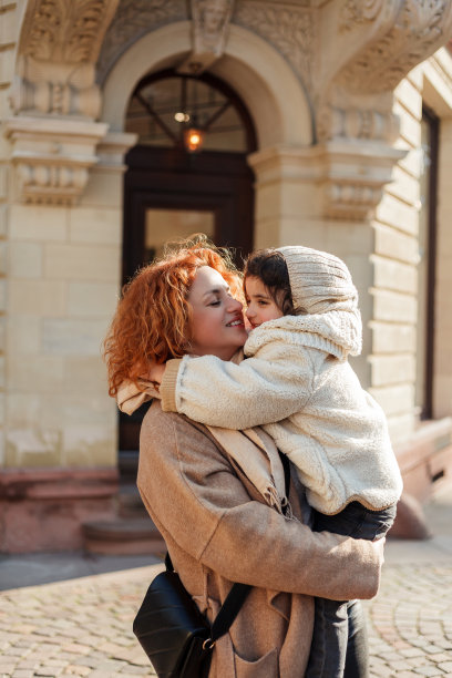 美丽的年轻母亲和可爱的4岁小女儿走在老城的中心。欧洲。幸福的家庭。图片下载