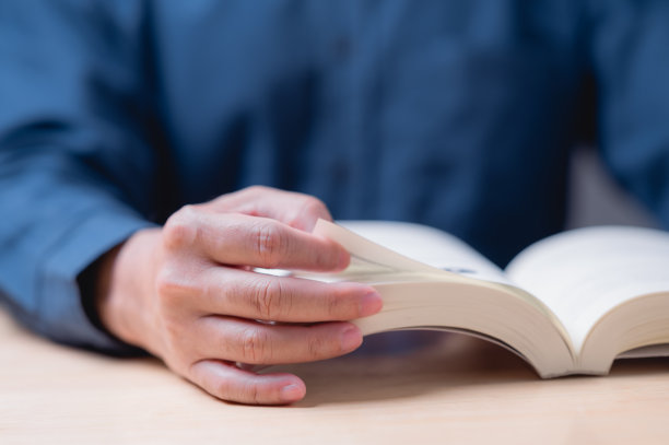 读书和学习书的概念。一个人正在看书，他的手放在书页上。这本书打开到一页，上面有一个人的照片图片下载