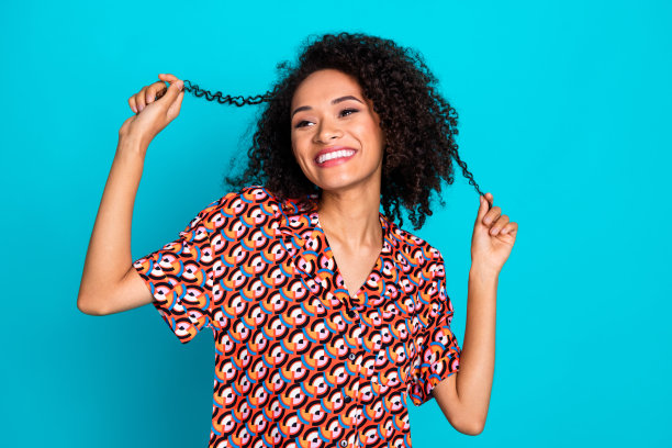 照片的少女可爱的女士穿着印花衬衫持有头发卷发孤立的蓝绿色背景图片下载