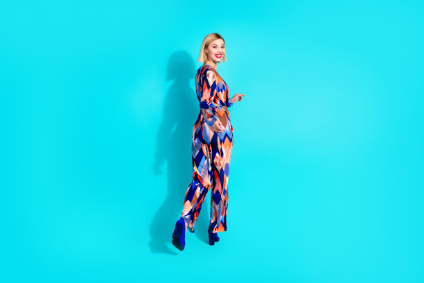 迷人的正面女性穿着印花服装的全长照片跑空空间孤立的蓝绿色背景图片下载