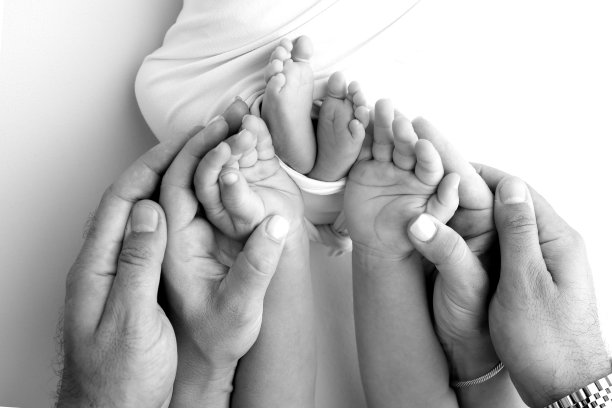 父亲的手掌，母亲的脚都抱着刚出生的婴儿在白色的背景。新生儿的脚放在父母的手掌上。孩子的脚趾、脚后跟和脚的照片图片下载