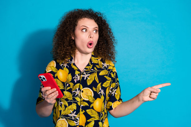 照片中震惊的可爱女孩穿着热带时尚的印花衣服，看起来像蓝色背景上的空白空间图片下载