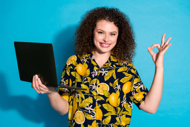 照片可爱可爱的有趣的女孩穿着时髦的热带印花衣服ok标志很好的反馈孤立的蓝色背景图片下载