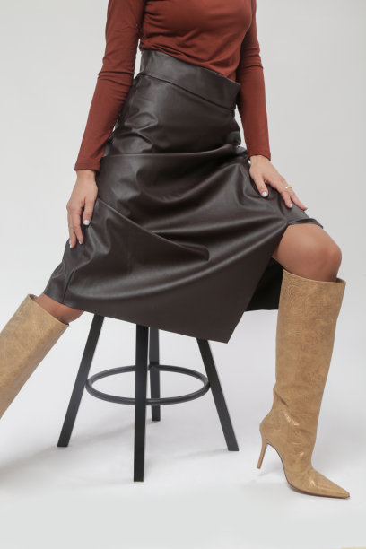 系列工作室女模特的照片，棕色衬衫和皮革中长裙和高膝靴，秋冬时装系列。图片下载