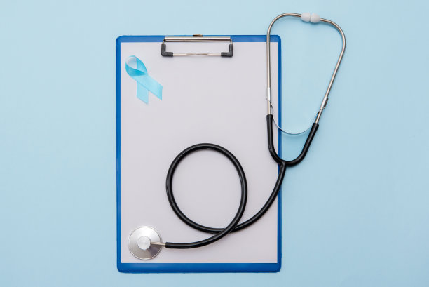 蓝色癌症前列腺意识带和听诊器在蓝色背景白纸剪贴板上图片下载