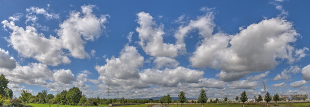 蓝天积云的全景照片，积云和晴朗天气的云和公园的建筑物正在建设中图片下载