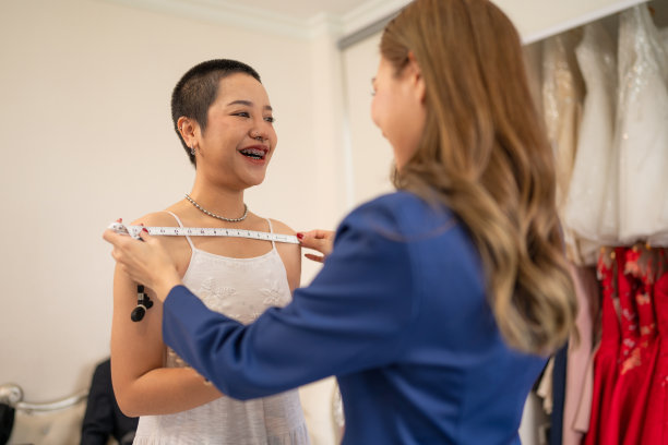 迷人的设计师女孩在婚纱上使用卷尺。图片下载