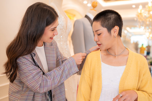 迷人的设计师女孩在婚纱上使用卷尺。图片下载