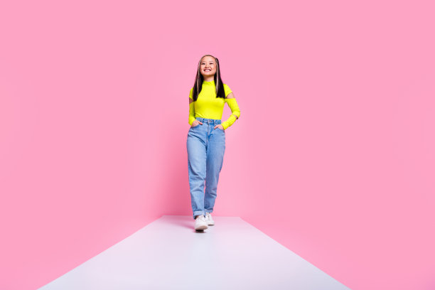 中国女孩染发的照片，穿着黄色高领毛衣，伸出舌头，在粉红色的背景上分开辫子图片下载