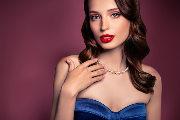 照片的女士穿着蓝色晚礼服触摸豪华珍珠吊坠孤立的棕色背景图片下载