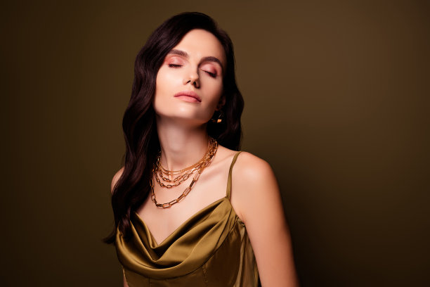 可爱的梦幻迷人的女士的照片穿丝绸卡其色连衣裙珍贵的配件孤立的棕色背景图片下载