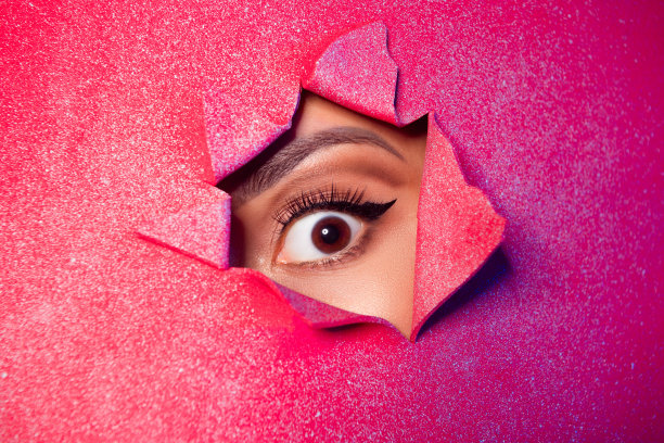 照片惊奇的女孩眼睛化妆看撕裂的红色闪闪发光的纸标识牌图片下载