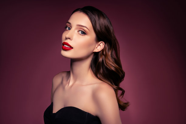 照片的高加索女士黑发与化妆看起来穿黑色时尚礼服孤立的棕色背景图片下载