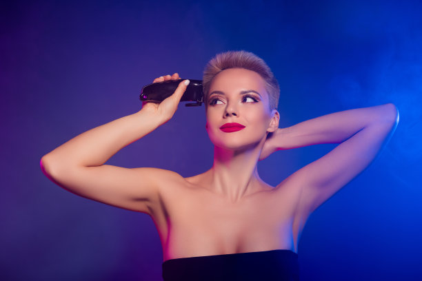 照片中的女孩穿着黑色的裙子，用剪发器在渐变发光的霓虹灯背景下理发图片下载