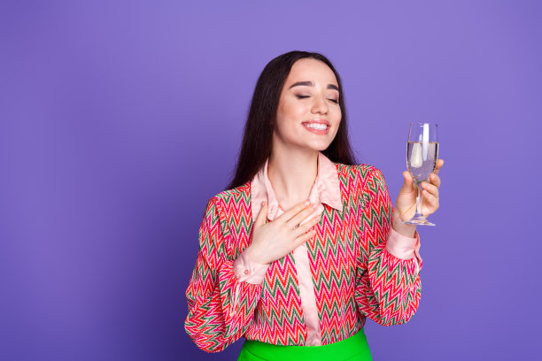 漂亮的年轻女孩的照片肖像享受假日香槟穿时髦的粉红色服装孤立的紫色背景图片下载