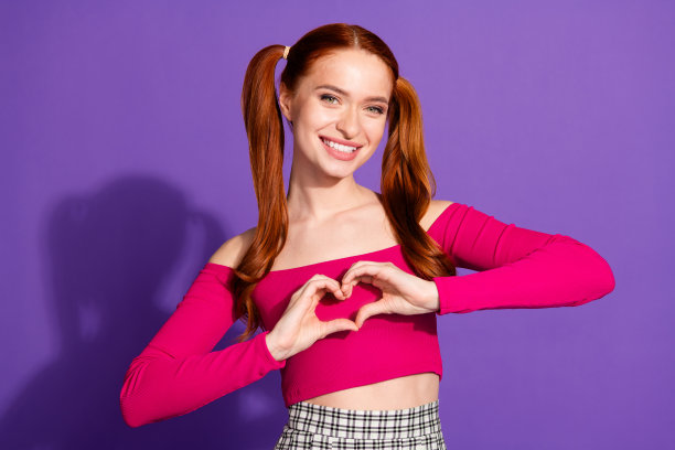 迷人的年轻女子的照片肖像显示心脏姿态穿着时尚的粉红色衣服孤立在紫罗兰色的背景图片下载