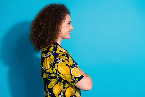 漂亮可爱的开朗女孩穿着热带时尚印花衣服的照片，在蓝色背景上呈现出孤立的空白空间图片下载