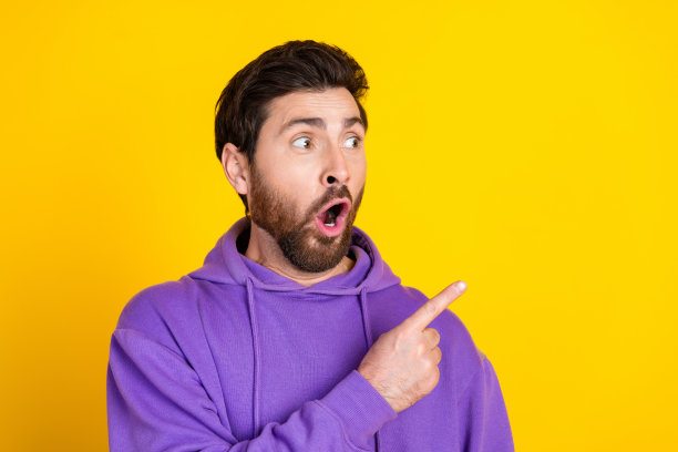 无语男子的照片，时尚的鬃毛穿着紫色卫衣，直接看着黄色背景上孤立的销售空间图片下载