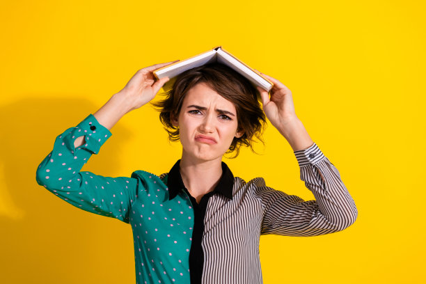 照片中悲伤沮丧的女人穿着时髦的衣服，拿着书，把坏心情孤立在黄色的背景上图片下载