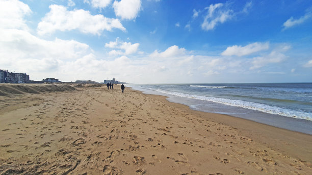 美丽的海滩，散步的人，很多的沙子，天空和酒店。图片下载