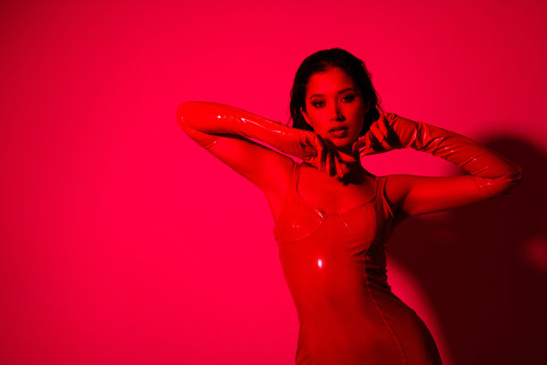 照片的华丽的年轻女孩触摸柔软的皮肤，脸穿红色的皮衣孤立的红色霓虹灯背景图片下载