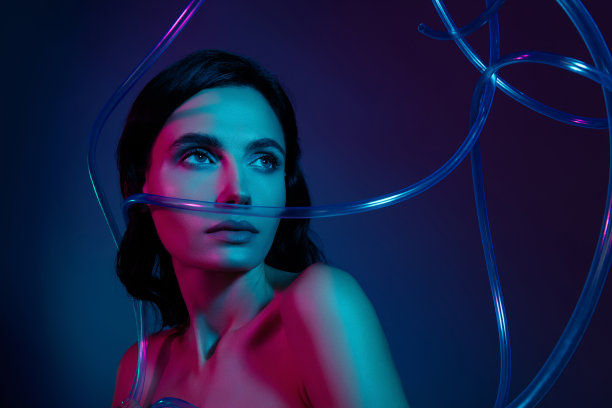 照片的女人看塑料电缆隔离在黑暗的紫外线霓虹灯色背景图片下载