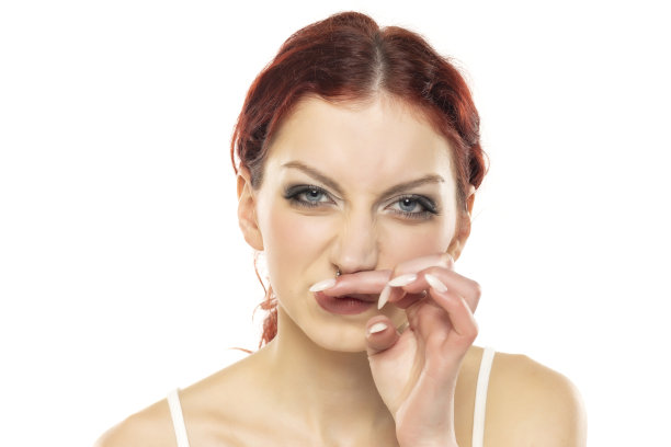 一个年轻的红发女人在白色的画室背景上鼻子发痒。图片下载