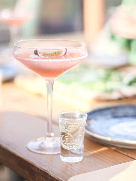 在一个漂亮的玻璃杯里盛有百香果的酒精饮料，在木桌上放一杯伏特加图片下载