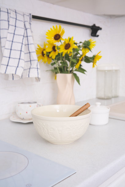 家庭厨房夏季室内-碗与面团，碗糖，一杯茶，陶瓷花瓶与鲜花在现代厨房的餐桌上。图片下载