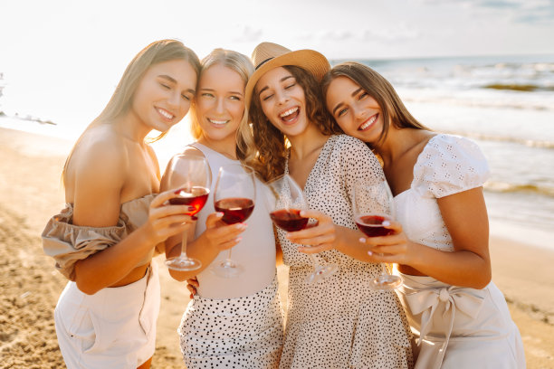 一群漂亮的女性朋友在沙滩上欢聚、干杯、喝酒、野餐。图片下载