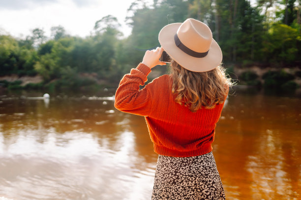 年轻的女游客拿着专业相机拍摄大自然的照片。图片下载