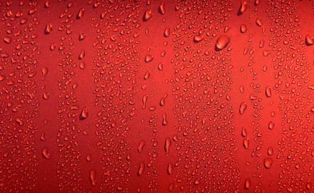 液体滴在一瞥强烈的红色表面。彩色液滴背景照片图片下载