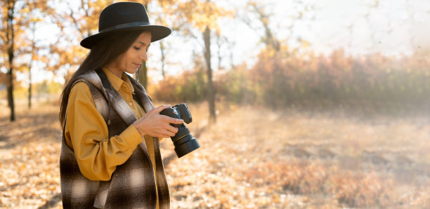 高加索摄影师，创造惊人的照片。站在空地上，手里拿着相机，看着镜头。横幅。图片下载