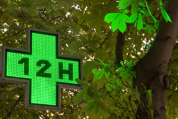 药房指示标志，一个发光的绿色十字标志，表明药房正在营业并提供服务。图片下载