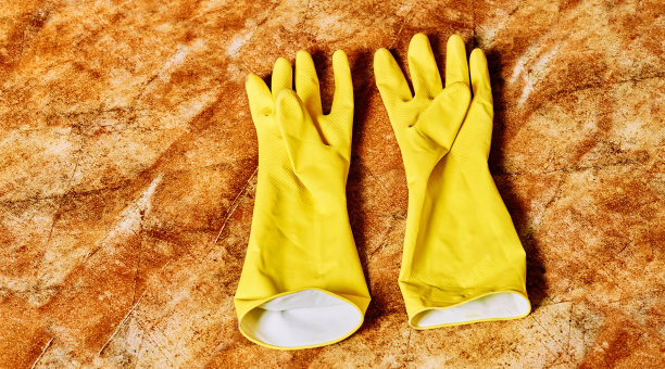 棕色大理石地板上戴着黄色橡胶手套图片下载