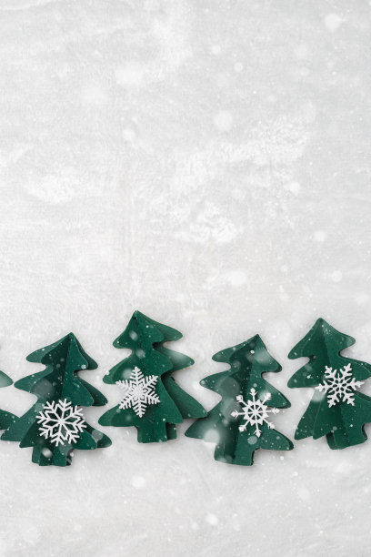 圣诞树剪纸，寒假背景，雪花飘飘。手工制作的绿色冷杉装饰雪花在白色的皮毛。唯美的顶视图，极简的平面布局趋势格局，节日心情愉快图片下载
