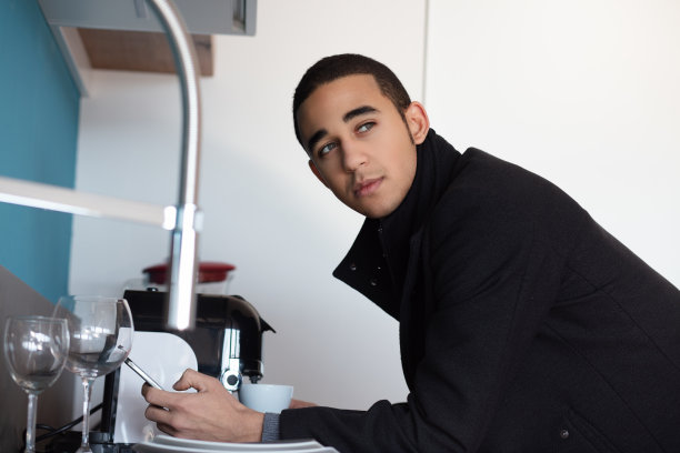 年轻的商人在厨房洗盘子时看向别处图片下载